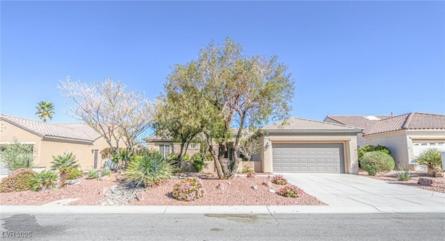view of front of house with a tiled roof, concrete driveway, stucco siding, and an attached garage