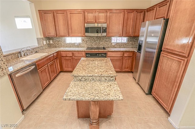 kitchen with stainless steel appliances, a center island, a sink, light stone counters, and backsplash