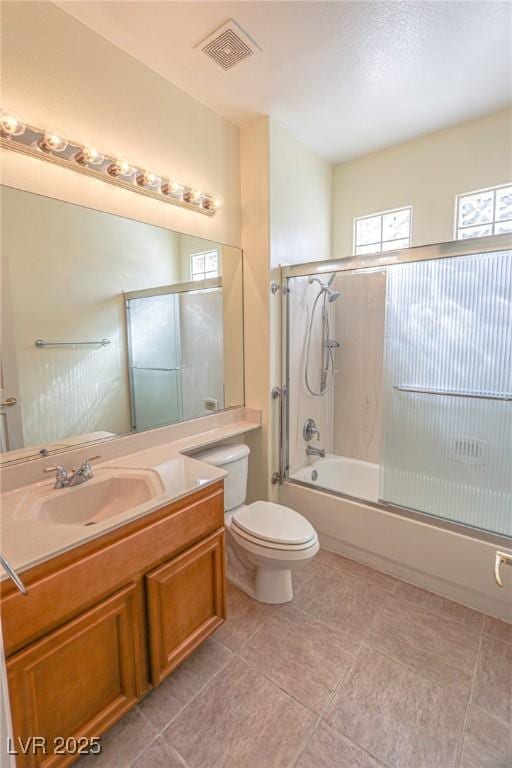bathroom featuring visible vents, toilet, tile patterned floors, vanity, and shower / bath combination with glass door