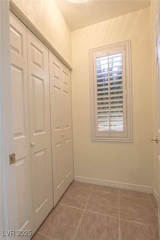 interior space featuring baseboards, a closet, multiple windows, and light tile patterned floors