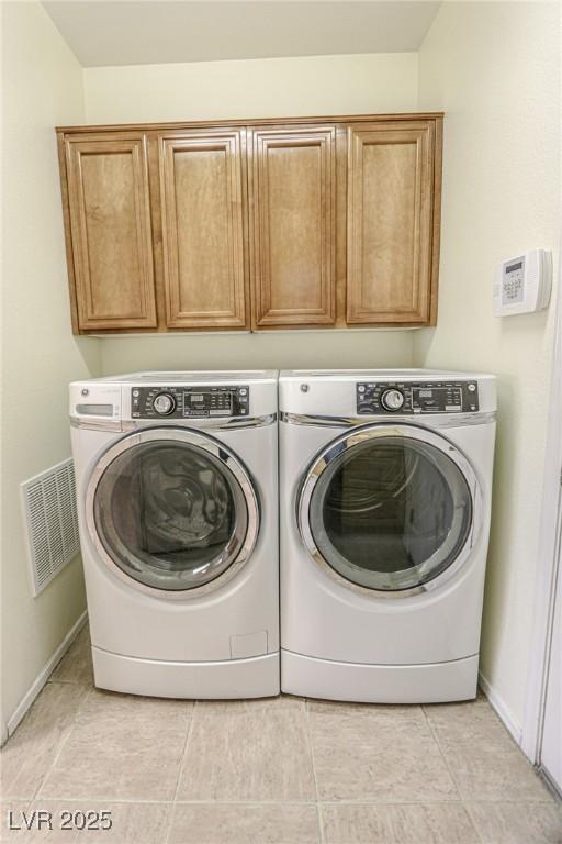 washroom with light tile patterned flooring, baseboards, visible vents, washer and dryer, and cabinet space