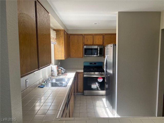2541 Love St, Las Vegas, NV 89121 - kitchen with appliances with stainless steel finishes, tile countertops, a sink, light tile patterned floors, and brown cabinets