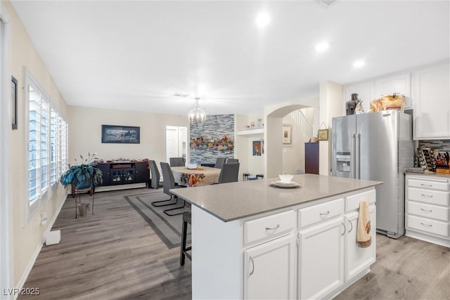9578 Teton Vista Ave, Las Vegas, NV 89117 - kitchen with arched walkways, stainless steel refrigerator with ice dispenser, light wood-style floors, open floor plan, and a center island