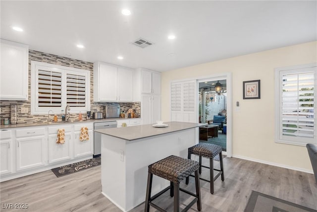 9578 Teton Vista Ave, Las Vegas, NV 89117 - kitchen featuring visible vents, tasteful backsplash, white cabinetry, a breakfast bar area, and stainless steel dishwasher