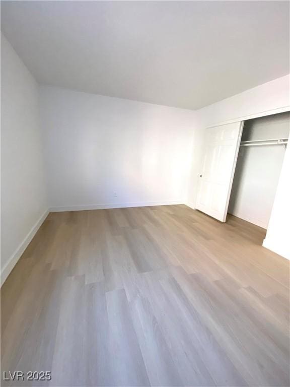 unfurnished bedroom with a closet, baseboards, and wood finished floors