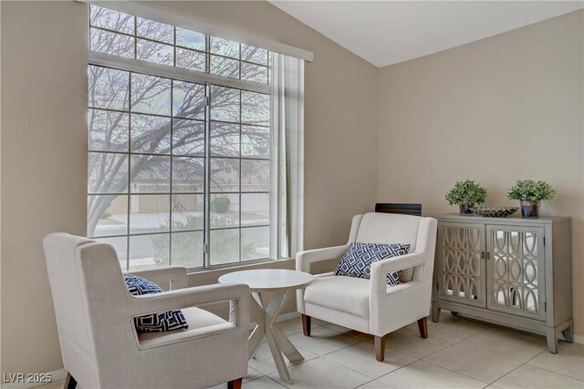 living area featuring a wealth of natural light, vaulted ceiling, and tile patterned floors