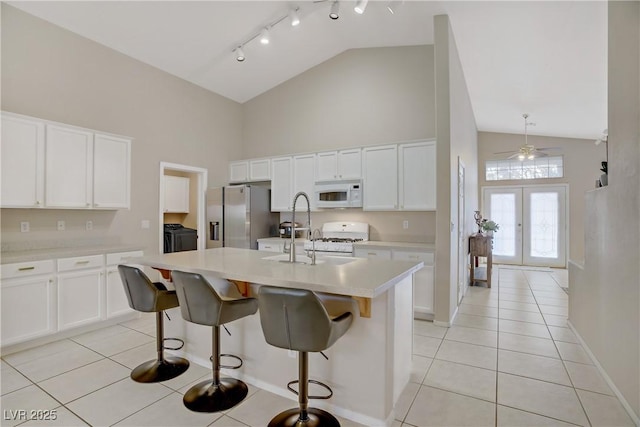 kitchen with light countertops, white cabinets, white appliances, washing machine and dryer, and light tile patterned floors