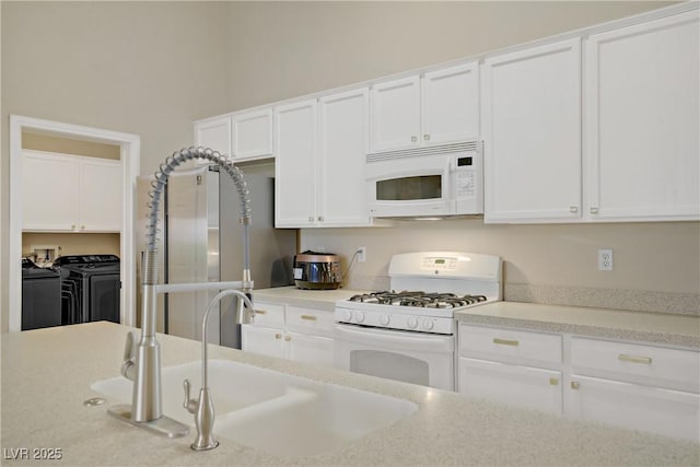 kitchen with white cabinetry, a sink, washing machine and dryer, and white appliances