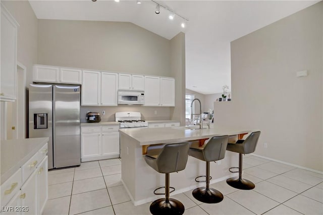 kitchen with white cabinetry, light countertops, white appliances, light tile patterned floors, and a sink