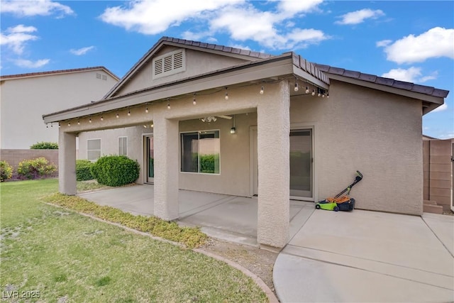 rear view of property featuring a lawn, stucco siding, and a patio area