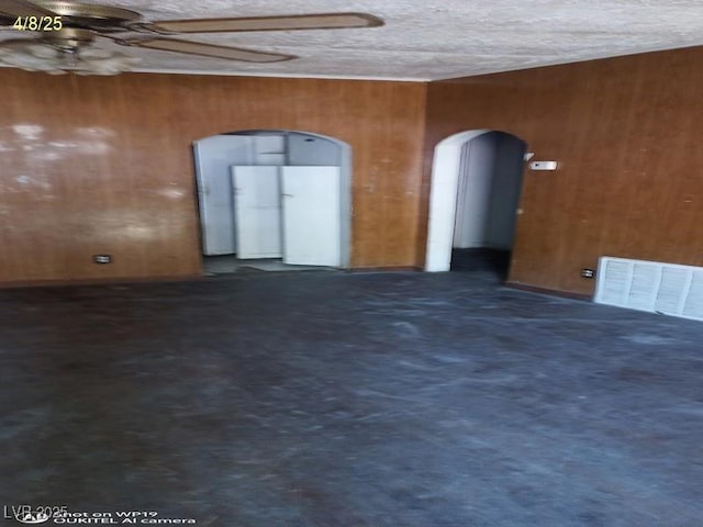 1550 Murry St, Ely, NV 89301 - spare room featuring arched walkways, a ceiling fan, wood walls, and a textured ceiling