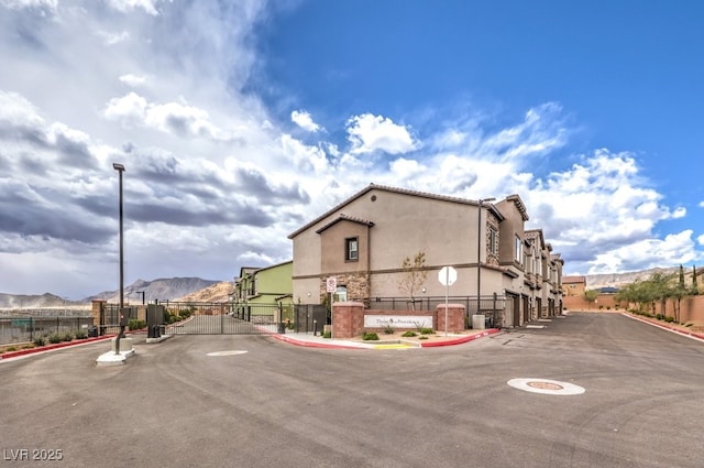 view of street featuring a gate, curbs, street lights, a gated entry, and a mountain view