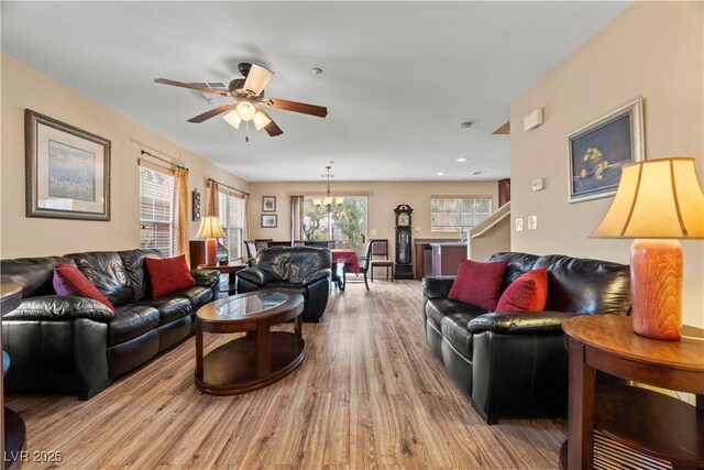 living area featuring ceiling fan with notable chandelier and light wood finished floors