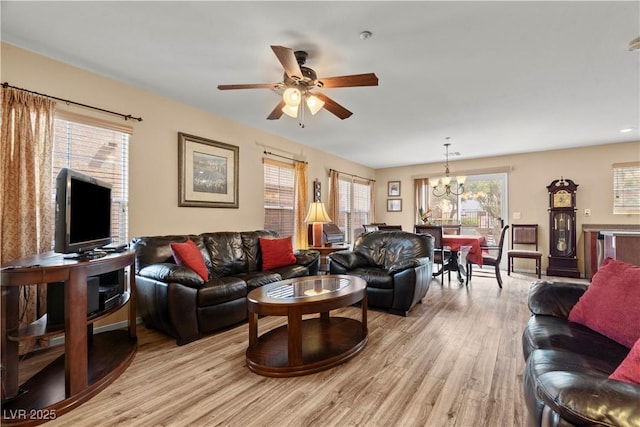 living area featuring light wood-style floors and ceiling fan with notable chandelier