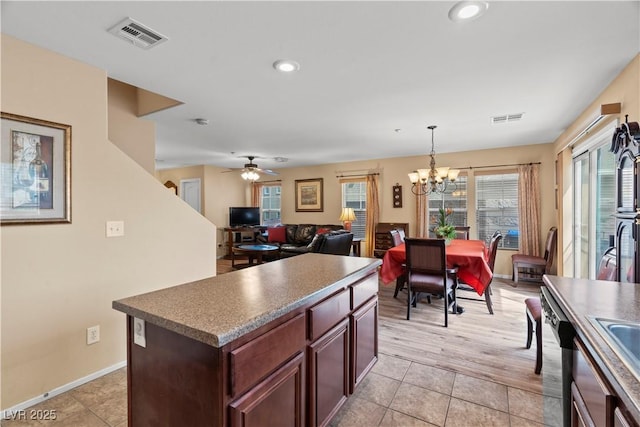 kitchen with stainless steel dishwasher, visible vents, ceiling fan with notable chandelier, and a kitchen island