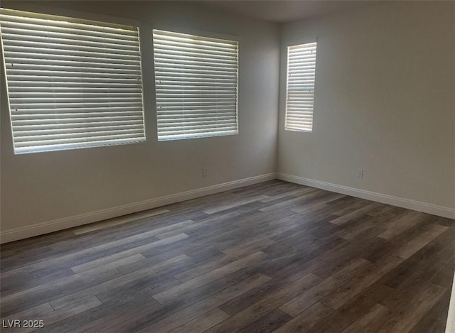 spare room featuring baseboards and dark wood-style flooring