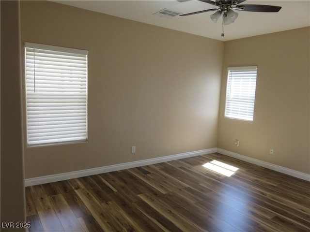spare room with baseboards, dark wood-style flooring, visible vents, and a ceiling fan
