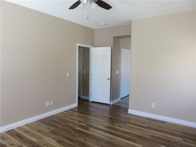 unfurnished room with baseboards, dark wood-type flooring, and a ceiling fan