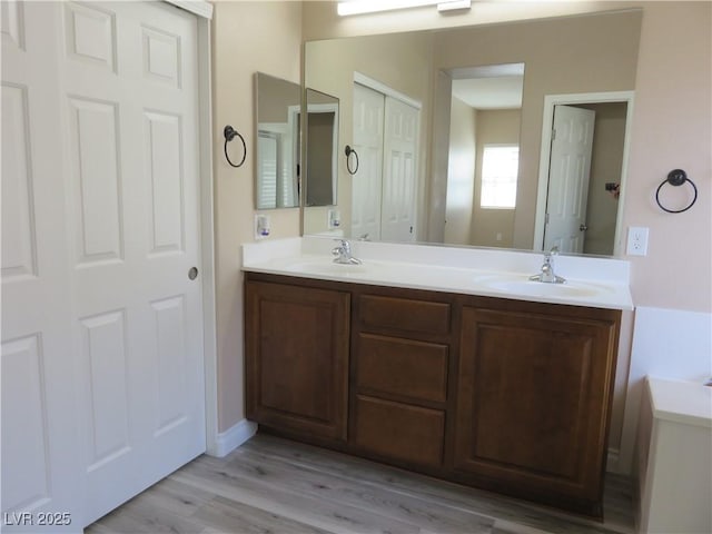 bathroom with double vanity, a sink, and wood finished floors