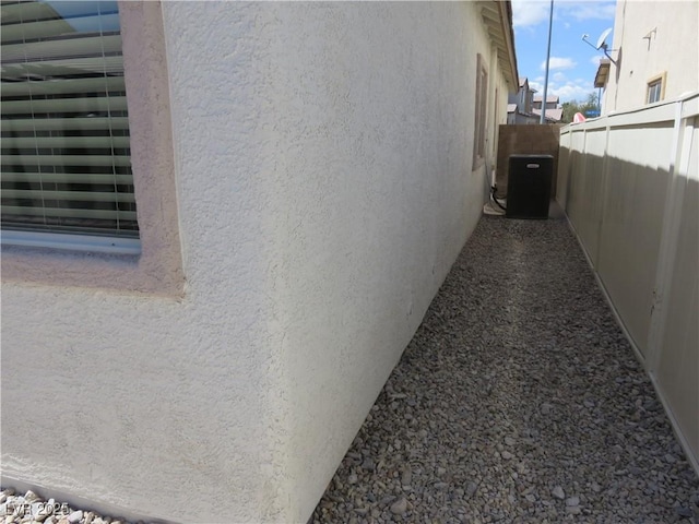 view of home's exterior featuring stucco siding, fence, and central AC