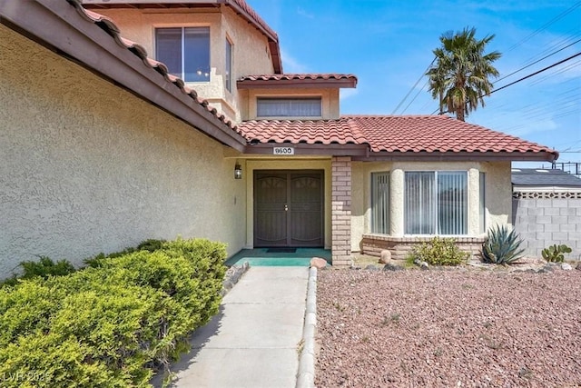property entrance with stucco siding and a tiled roof