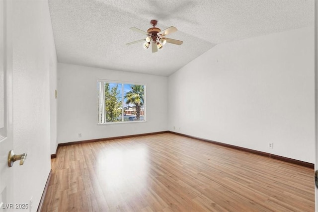 spare room featuring a textured ceiling, light wood-type flooring, vaulted ceiling, and a ceiling fan