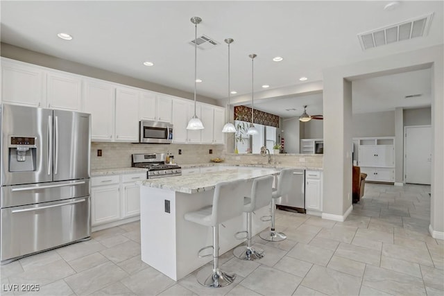 651 Penshaw Bridge Ave, Las Vegas, NV 89178 - kitchen with appliances with stainless steel finishes, backsplash, white cabinetry, ceiling fan, and a breakfast bar area