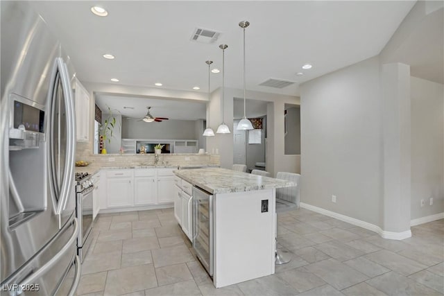 651 Penshaw Bridge Ave, Las Vegas, NV 89178 - kitchen featuring appliances with stainless steel finishes, ceiling fan, wine cooler, light stone counters, and a kitchen breakfast bar