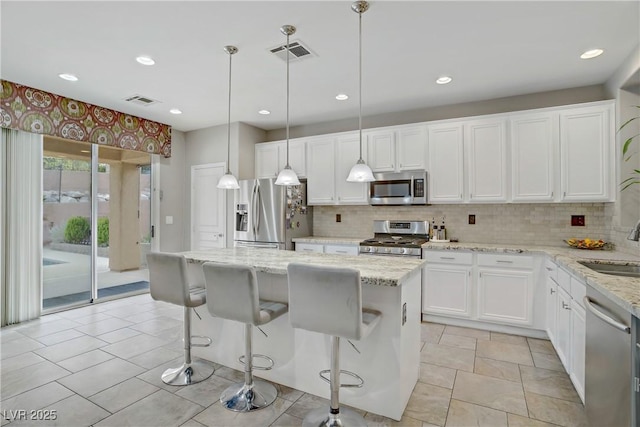 651 Penshaw Bridge Ave, Las Vegas, NV 89178 - kitchen with appliances with stainless steel finishes, a kitchen island, white cabinets, decorative backsplash, and light stone counters