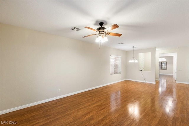 unfurnished room with baseboards, a ceiling fan, wood finished floors, and visible vents