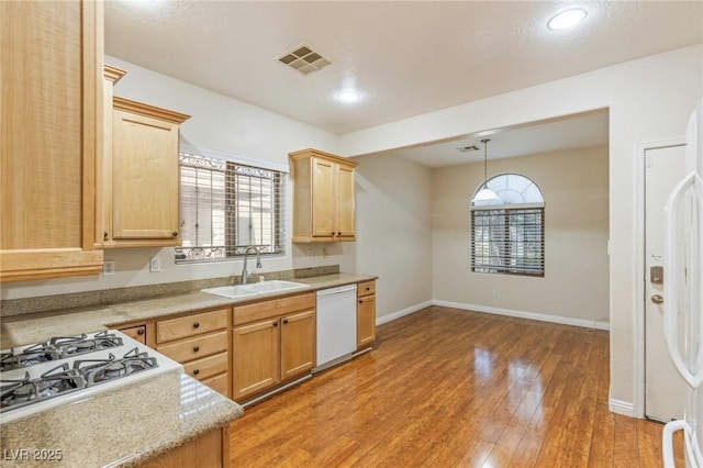 kitchen featuring white dishwasher, a sink, light countertops, baseboards, and visible vents