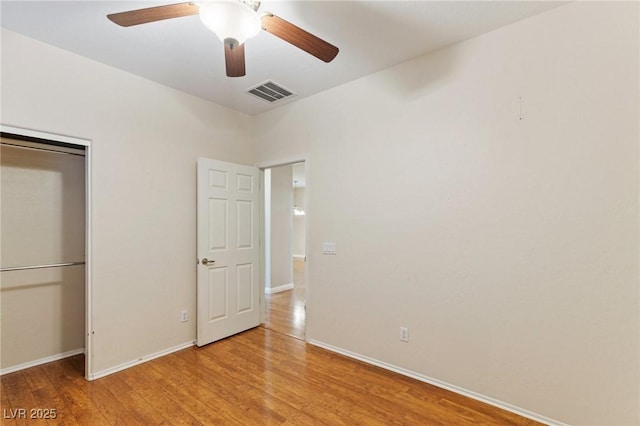 unfurnished bedroom with a ceiling fan, visible vents, wood finished floors, baseboards, and a closet