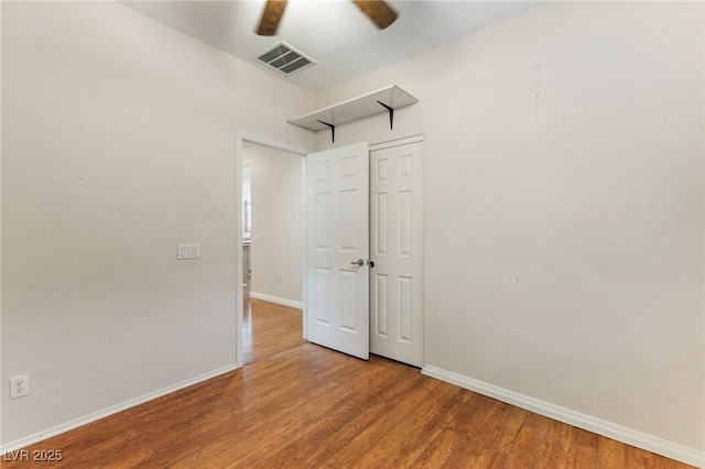 unfurnished room featuring baseboards, visible vents, ceiling fan, and wood finished floors