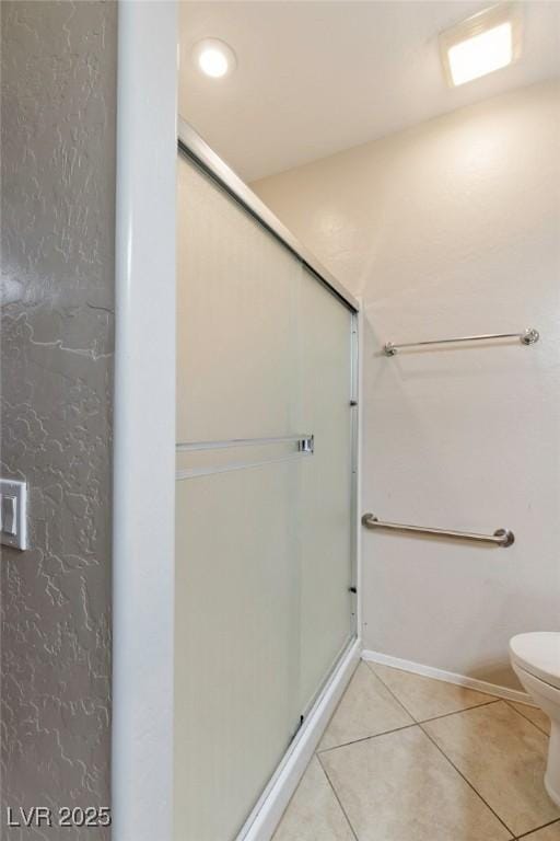 bathroom with toilet, baseboards, a shower stall, and tile patterned flooring