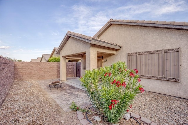 back of house with a fenced backyard, stucco siding, and a fire pit
