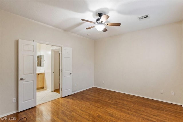 unfurnished bedroom with visible vents, ensuite bathroom, baseboards, a ceiling fan, and light wood-style flooring