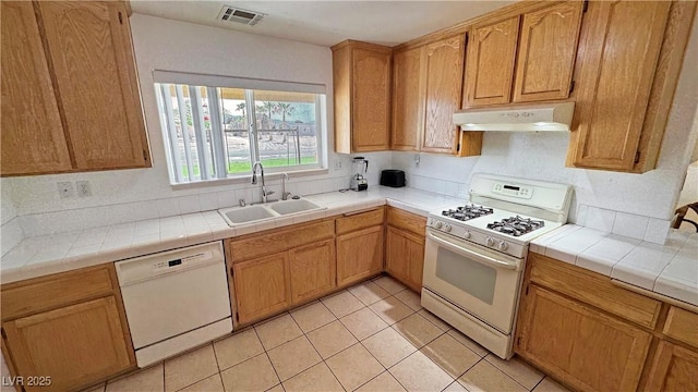 kitchen with a sink, white appliances, light tile patterned floors, under cabinet range hood, and visible vents