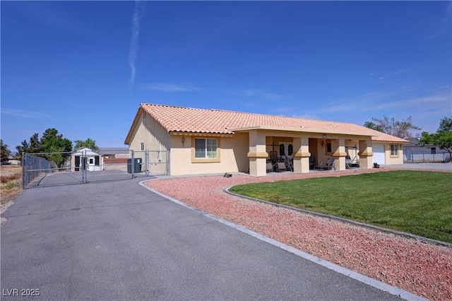 view of front of property featuring a front lawn, cooling unit, stucco siding, a gate, and a tiled roof