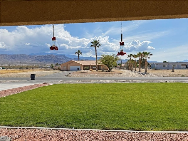 view of yard featuring an attached garage, driveway, and a mountain view