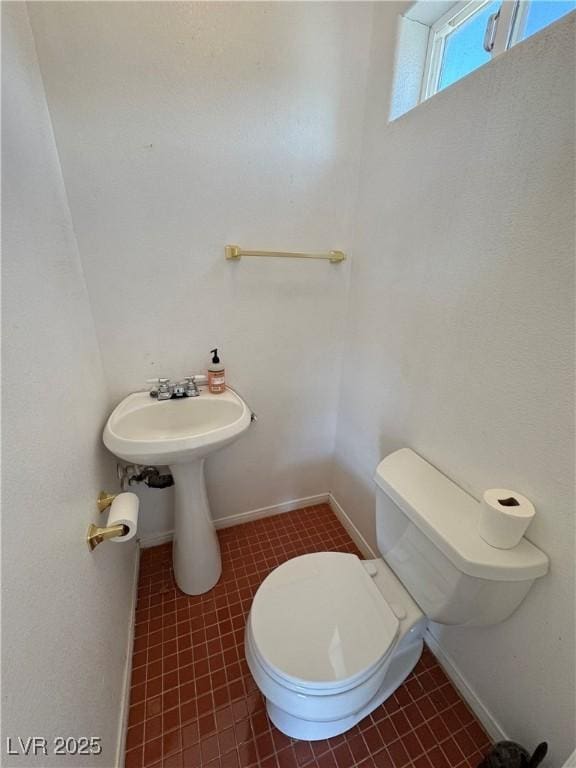 half bath with tile patterned flooring and toilet