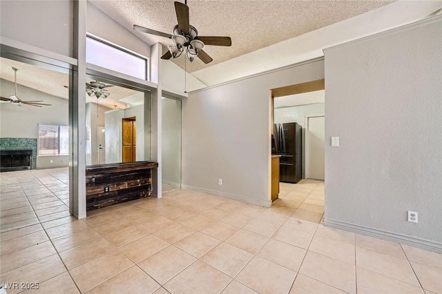 unfurnished room featuring a textured ceiling, ceiling fan, light tile patterned flooring, and vaulted ceiling