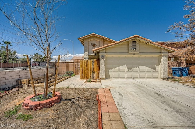 view of front facade with stucco siding, fence, a tile roof, and concrete driveway