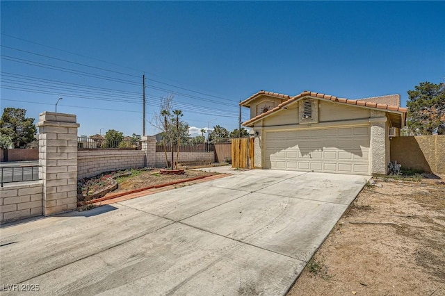 view of front of home featuring a tiled roof, fence, concrete driveway, and stucco siding