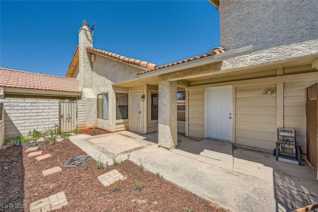 exterior space with a patio area, stucco siding, and a tile roof