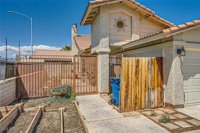 view of home's exterior with a gate, a garden, fence, and a tiled roof