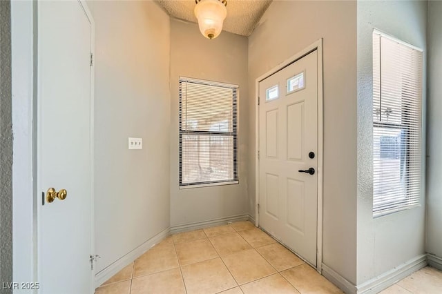 foyer featuring baseboards and light tile patterned floors