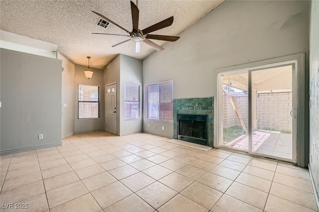 unfurnished living room featuring a ceiling fan, visible vents, a tiled fireplace, and light tile patterned floors