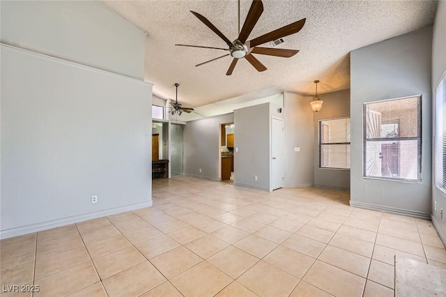 empty room with ceiling fan, a textured ceiling, visible vents, light tile patterned floors, and lofted ceiling