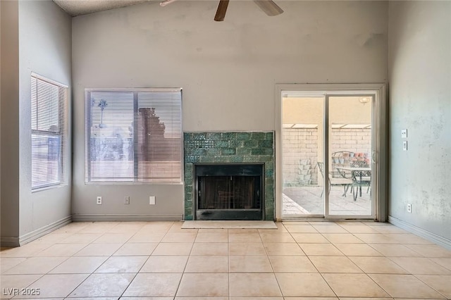 unfurnished living room with tile patterned floors, baseboards, a fireplace, and a ceiling fan