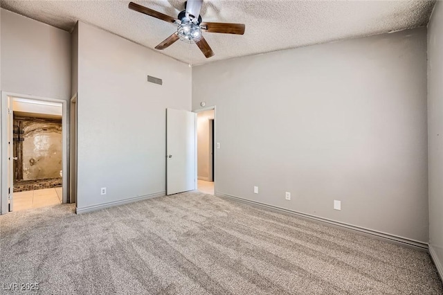 unfurnished bedroom featuring visible vents, a textured ceiling, baseboards, and light colored carpet